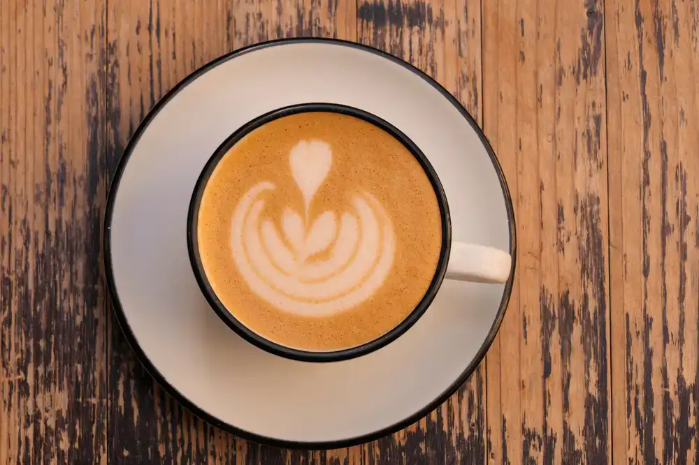 Ein professioneller Barista gießt kunstvoll einen perfekten Milchschaum in eine Kaffeetasse